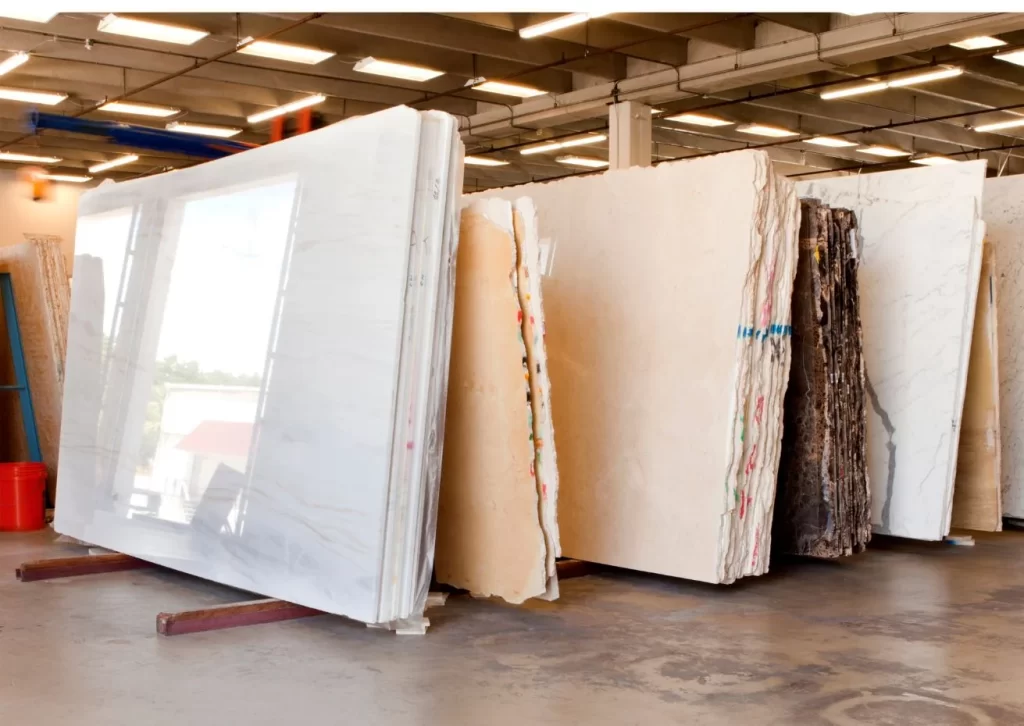 Large marble and granite slabs stored in a factory warehouse for countertop production.