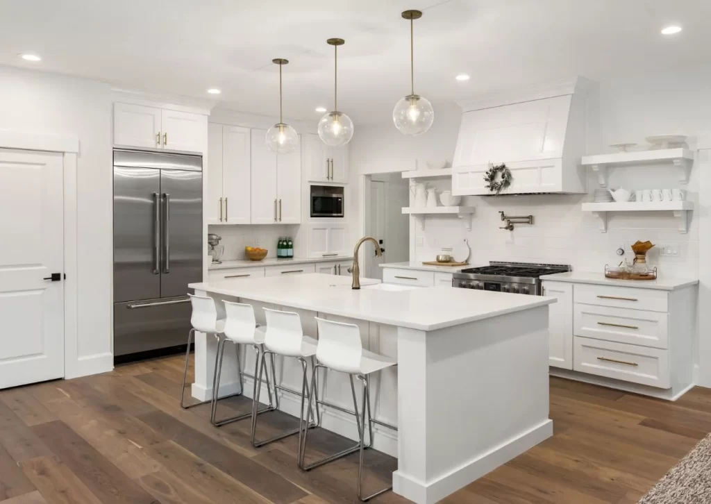 Bright modern kitchen with white cabinets, a large island, pendant lighting, and stainless steel appliances, perfect for a stylish and functional remodel.