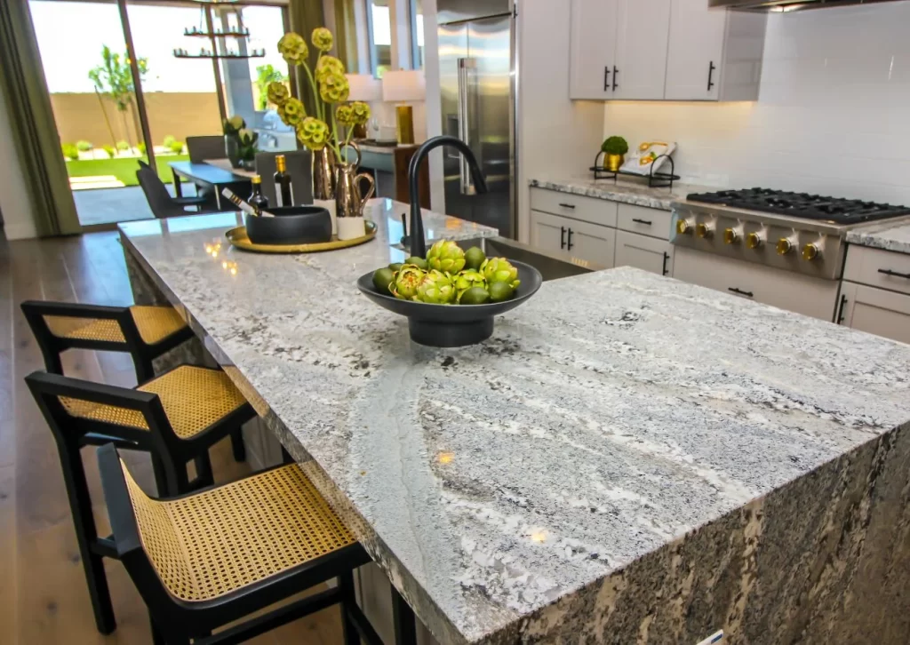 Modern kitchen featuring a large island with elegant marble countertops, black fixtures, and stylish decor, creating a luxurious and functional space."