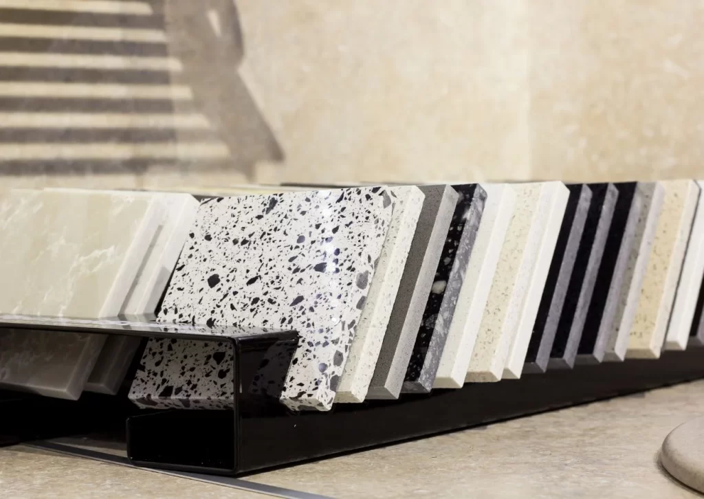 A collection of countertop material samples, including marble, granite, and quartz, displayed in a modern showroom