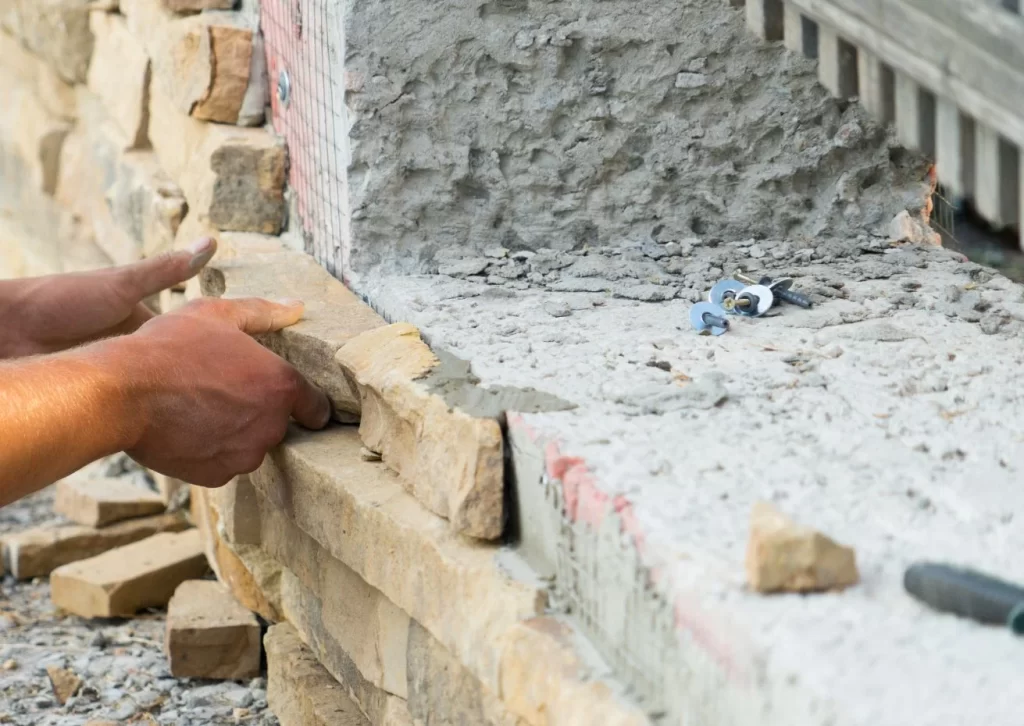 Close-up of a professional installing stone wall cladding on a concrete surface, showcasing the precision and craftsmanship involved."

SEO Keyphrase: "stone wall cladding installation